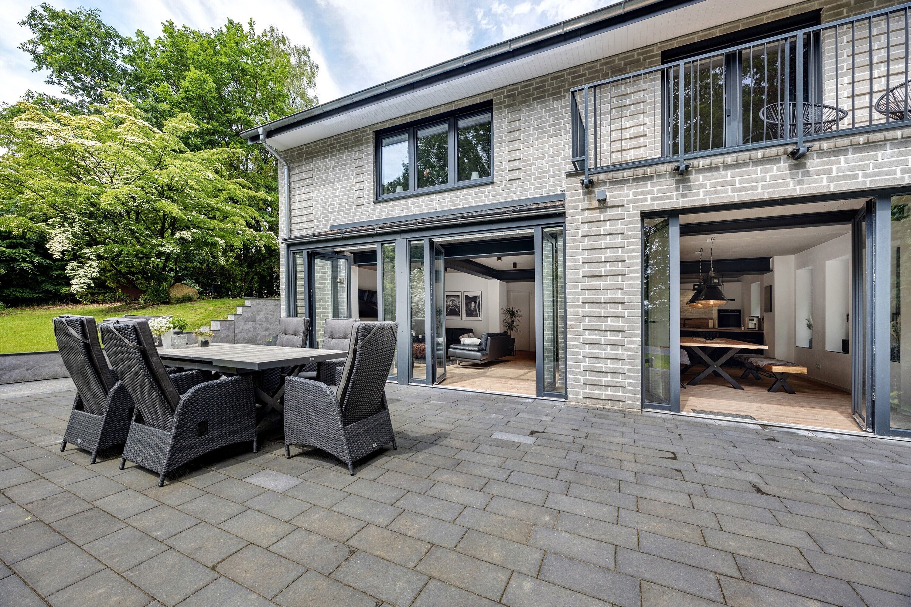Una casa moderna con patio, mobiliario exterior y una cocina a la vista.