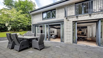 Una casa moderna con patio, mobiliario exterior y una cocina a la vista.