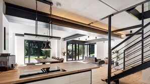 A modern kitchen with a wooden countertop, a built-in oven, and a sink. There is a staircase with a metal railing leading to an upper level.