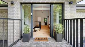 A modern building entrance with a brick facade, glass doors, and a wooden floor.