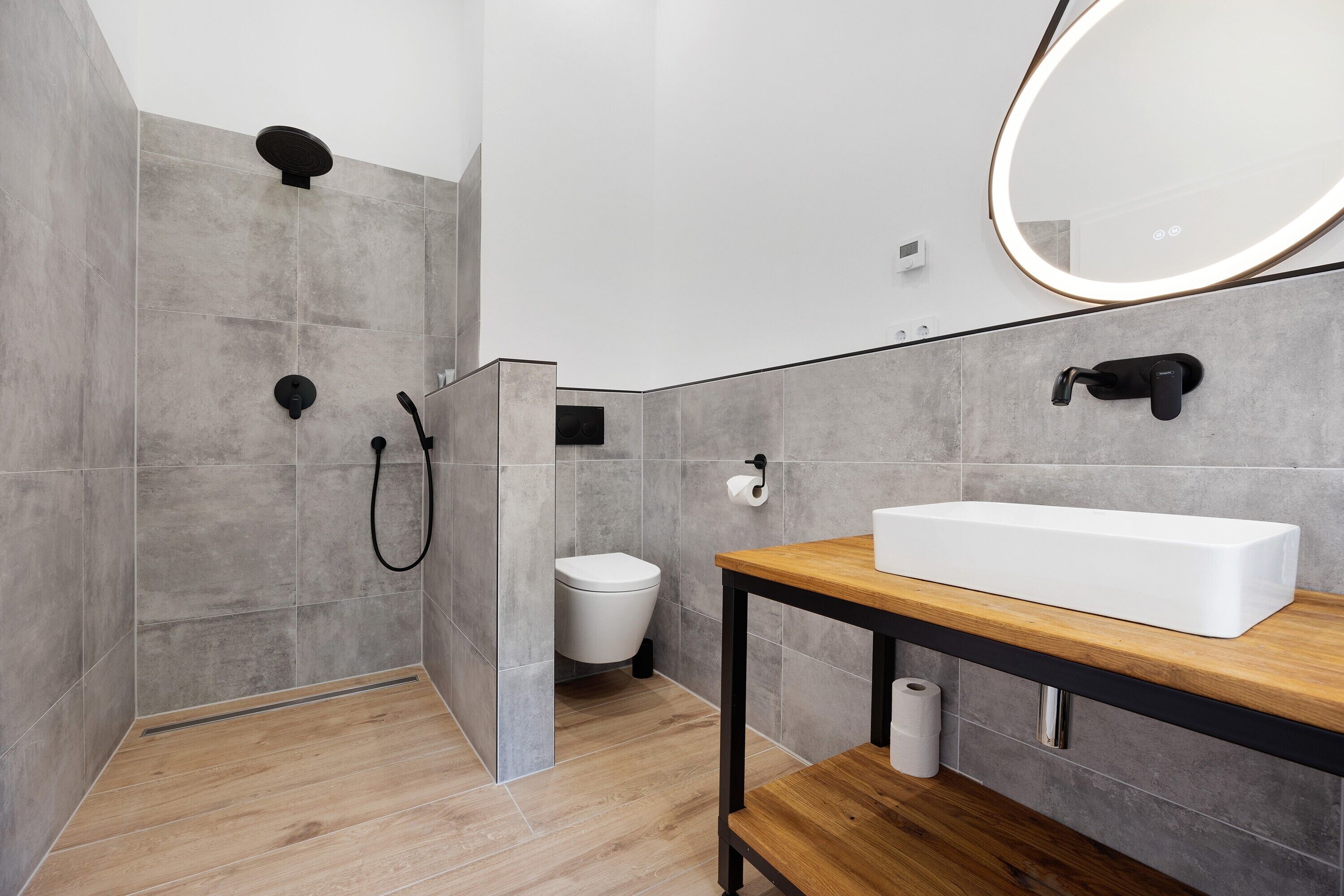 A modern bathroom with a shower, toilet, and a sink with a mirror.