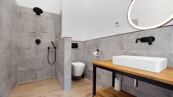 A modern bathroom with a shower, toilet, and a sink with a mirror.