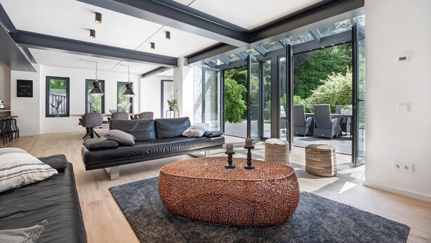 A modern living room with a sofa, coffee table, and large windows.