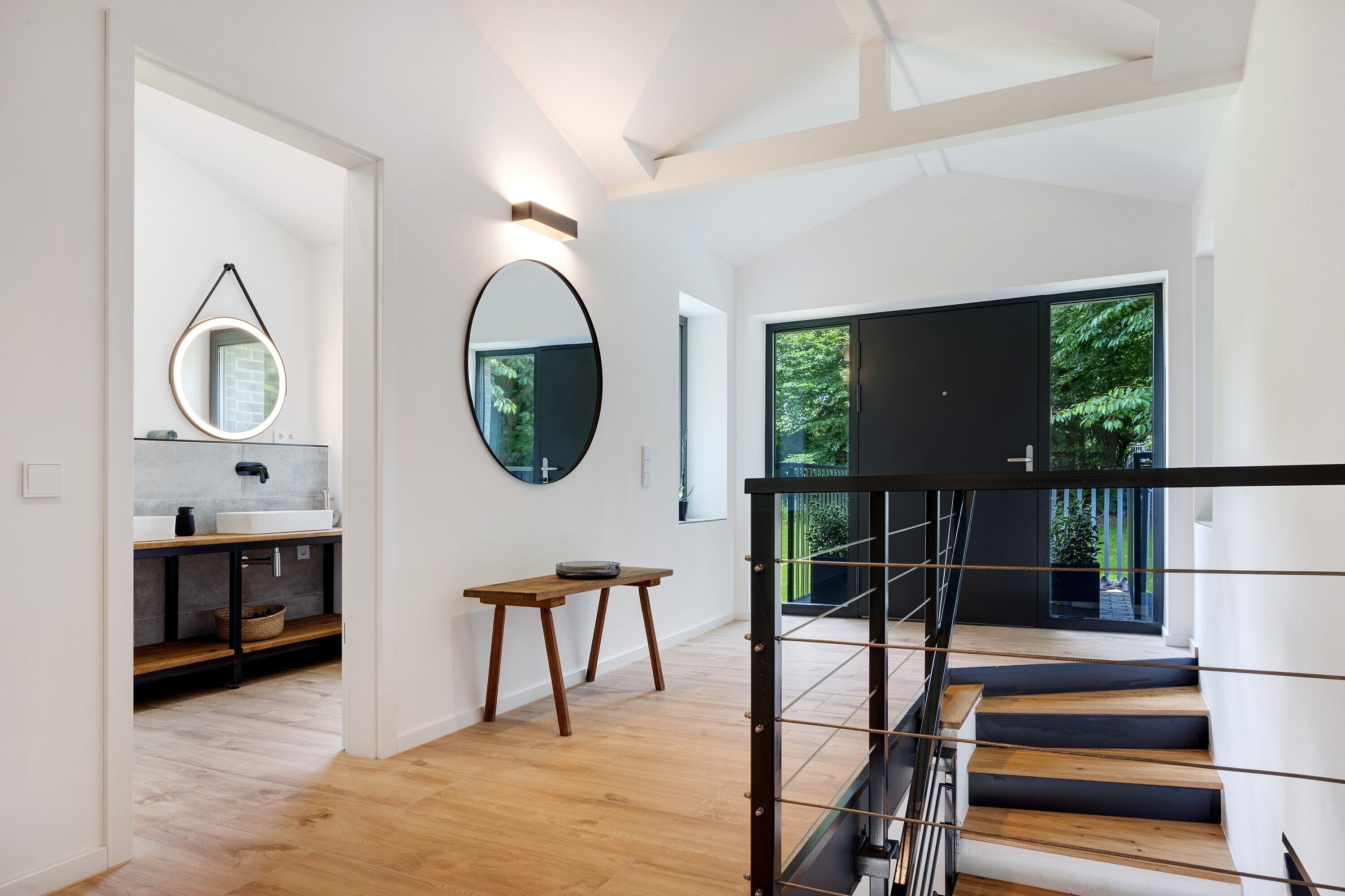 Ein modernes Interieur mit Treppe, Küchenbereich und großem Fenster.