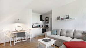 A compact living space with a kitchenette, a dining area, and a seating area with a sofa and a coffee table. - Apartment 'Hoern 1' with Wi-Fi (Nordstrand)