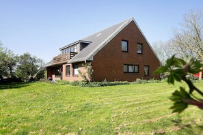 Une maison en briques avec un toit en pente et un petit balcon.