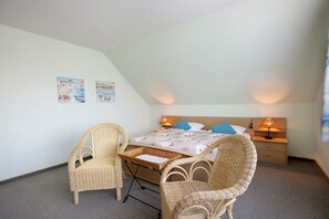 Une chambre à coucher avec un lit, deux fauteuils en osier, une table de chevet et une lampe.