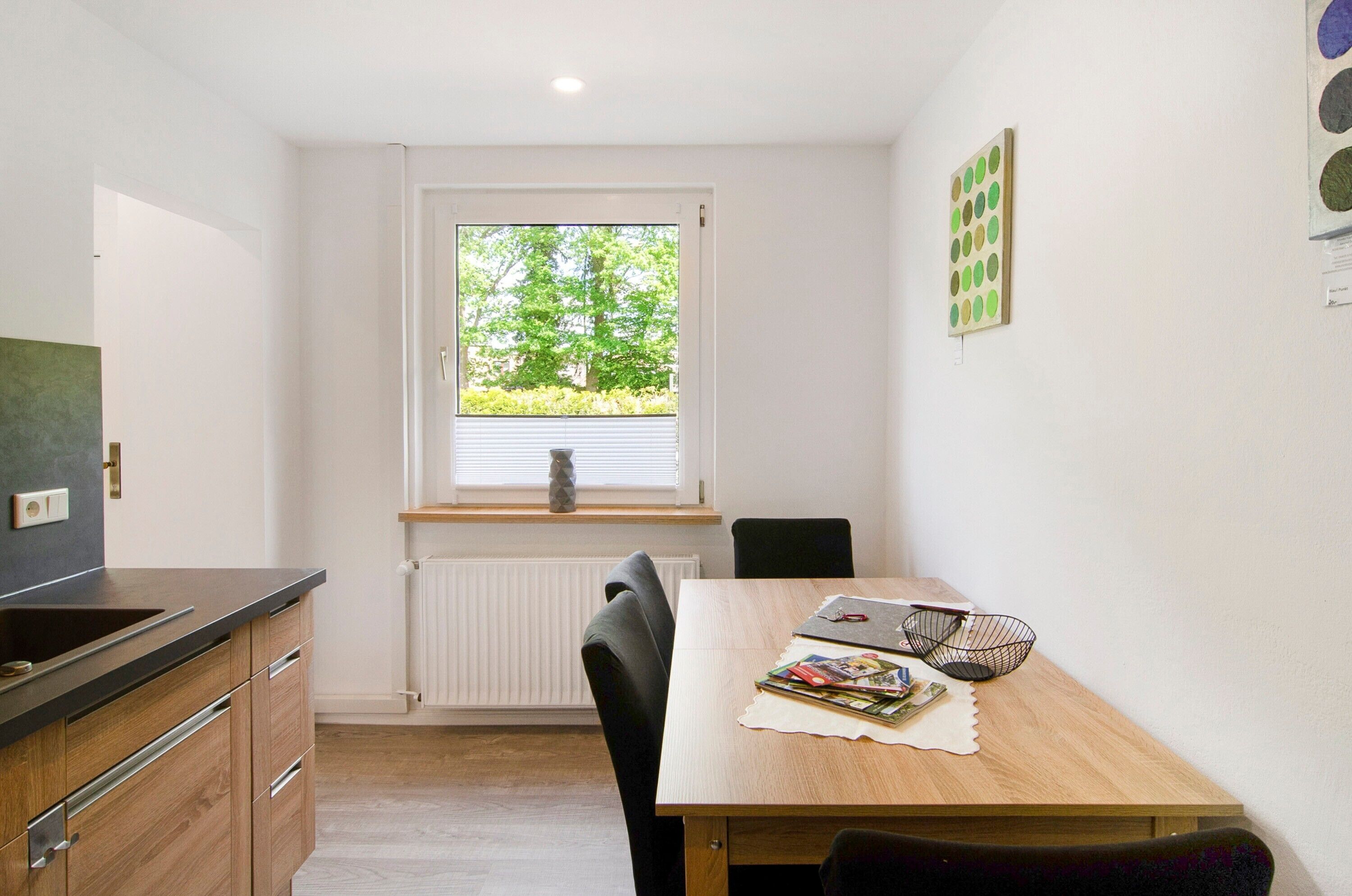 Une cuisine compacte avec une fenêtre, une table à manger et un petit coin salon.
