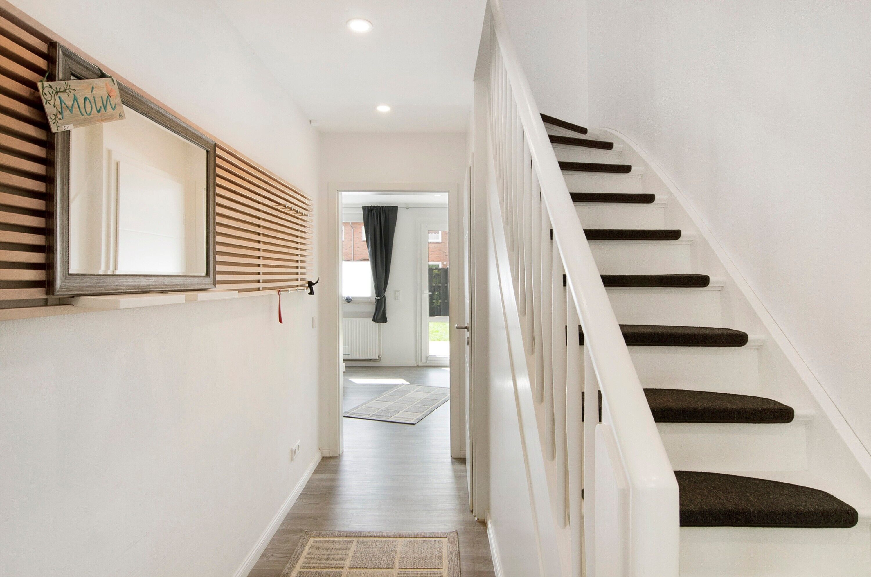 Un escalier menant à une pièce dont un mur est recouvert de lambris en bois et sur lequel on peut lire l’inscription « Moin ».