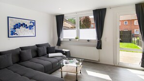 Una sala de estar moderna con un sofá gris, una mesa de centro de vidrio y una obra de arte en la pared.