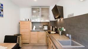 Una cocina moderna con armarios de madera, horno empotrado, cafetera y pileta de acero inoxidable.