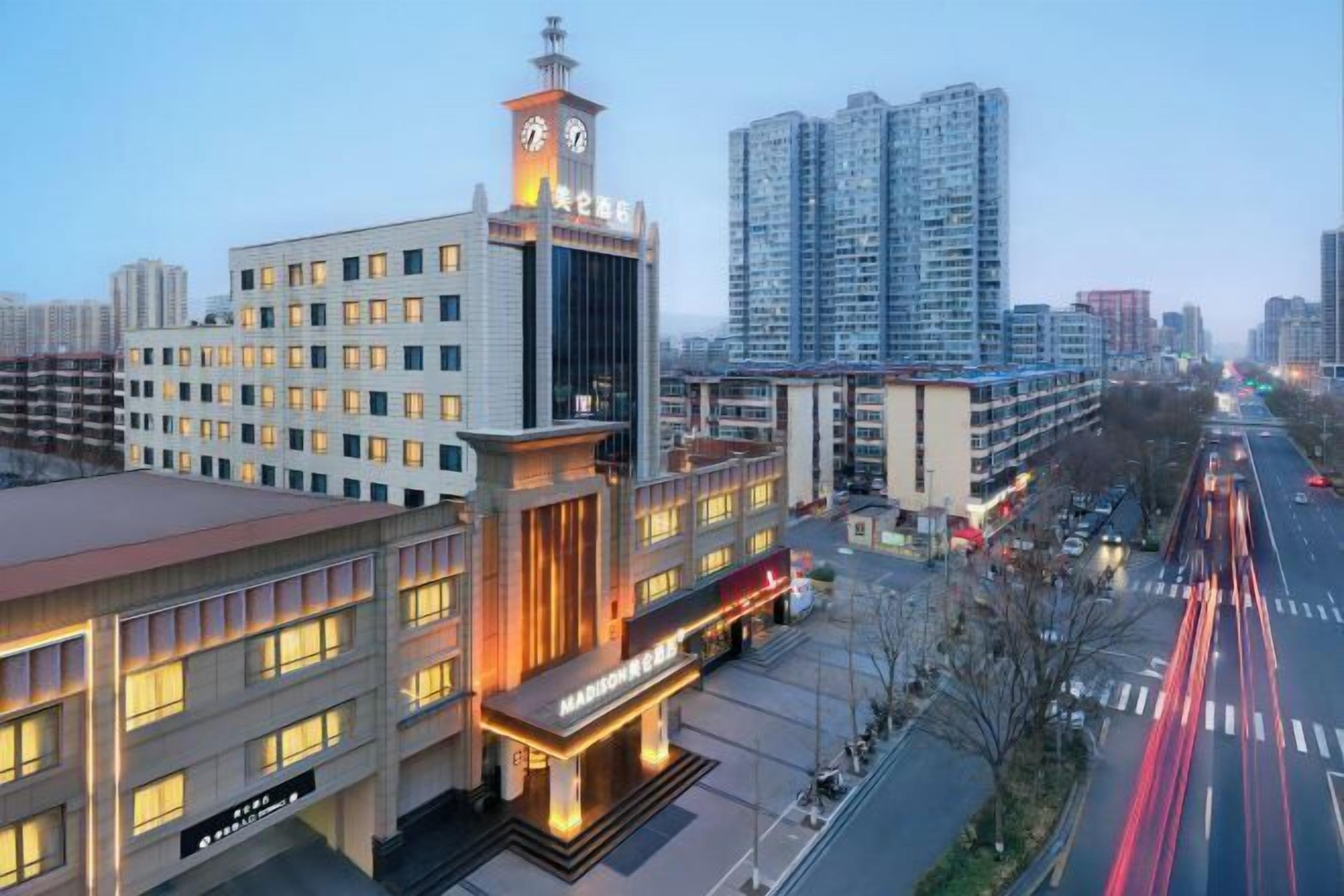 A hotel with a prominent clock tower, multiple floors, and a well-lit facade.