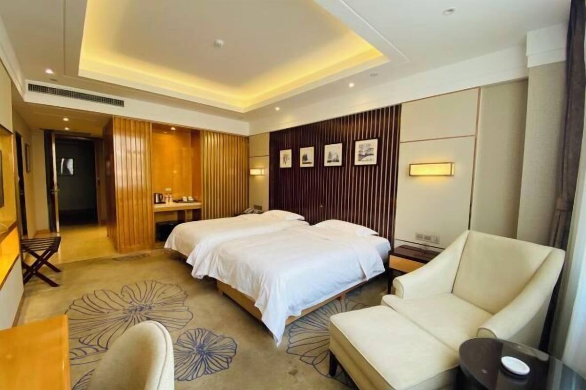 Ein Hotelzimmer mit zwei Betten, einer Couch, einem kleinen Tisch und einem dekorativen Teppich.