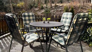 A patio with a round table and four chairs, surrounded by a wooden fence.