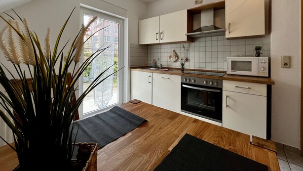A modern kitchen with white cabinets, a microwave, an oven, and a window with a view of buildings.