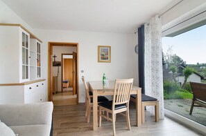 A dining area with a table, chairs, and a view through a large window.