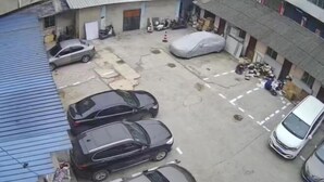 Een parkeerplaats met meerdere auto's, een overdekte auto en wat losse spullen.