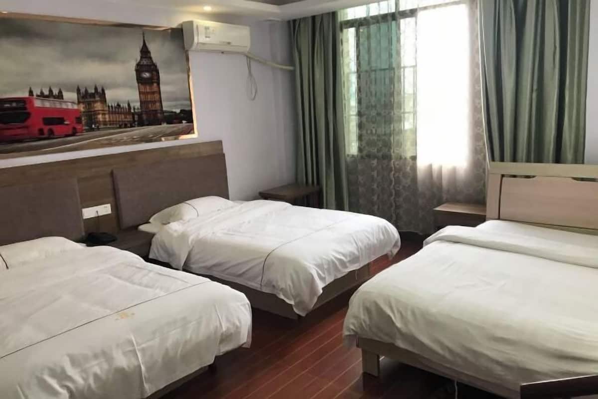 Une chambre d’hôtel avec deux lits simples, une tête de lit ornée d’un tableau représentant des monuments de Londres, une fenêtre avec des rideaux et une table de chevet.