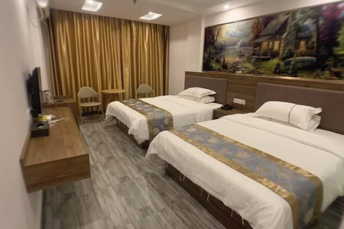 Une chambre d’hôtel avec deux lits, un bureau, une chaise et un tableau au mur.