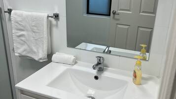Casa de banho com lavatório branco, espelho e porta-toalhas.