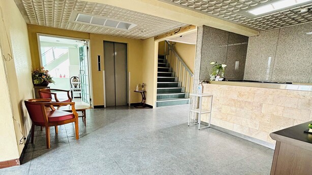 A spacious lobby with a reception desk, a staircase, and a seating area with chairs. - GREEN HOTEL AIZU (Aizuwakamatsu)