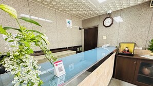 A reception desk with a glass top, a PayPay payment sign, a clock, and a security camera on the wall. - GREEN HOTEL AIZU (Aizuwakamatsu)