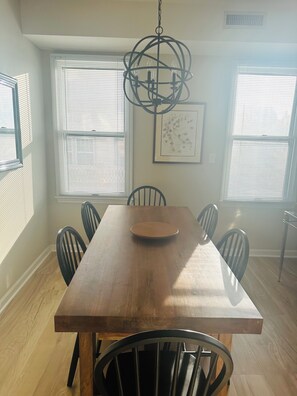 A dining area with a wooden table, six chairs, a chandelier, and large windows with blinds. - PERFECT LOCATION: 1 Block from the beach & close to Washington Mall  (Cape May)