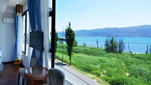 Un balcón con vista a un lago, una silla de mimbre y una pequeña mesa.