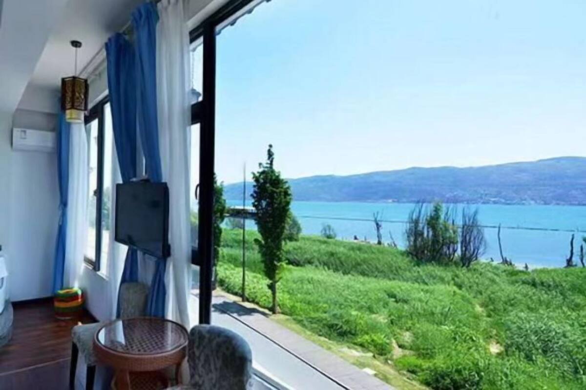 Un balcon donnant sur un lac, une chaise en osier et une petite table.