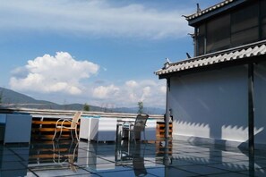 A rooftop terrace with a traditional building, a table, chairs, and a view of the mountains. - Erhaike Inn (Dali City)