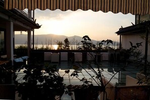 A terrace with a view of mountains and a body of water during sunset.