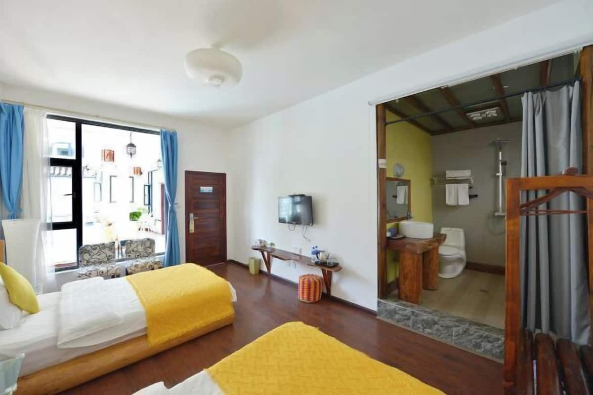 Une chambre d’hôtel avec deux lits, une télévision, une salle de bain avec douche et vue sur la rue.
