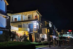 A multi-story building with balconies, illuminated signs, and a pedestrian walkway.