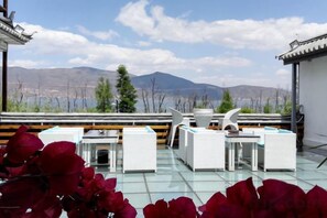 A rooftop terrace with outdoor furniture, a view of mountains, and a traditional building structure. - Erhaike Inn (Dali City)