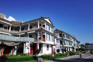 A row of traditional-style buildings with multiple stories, balconies, and a clear blue sky. - Erhaike Inn (Dali City)