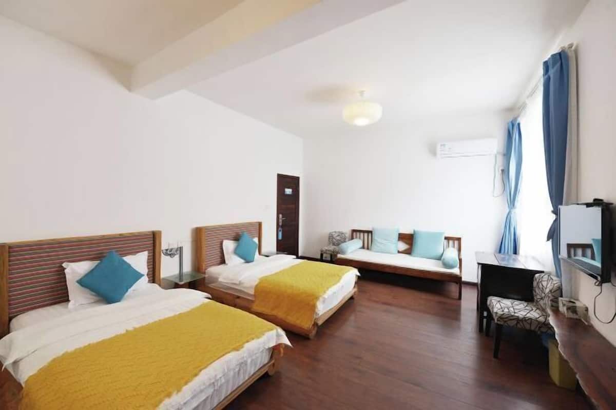 Une chambre d’hôtel avec deux lits, un bureau, une chaise et un téléviseur.