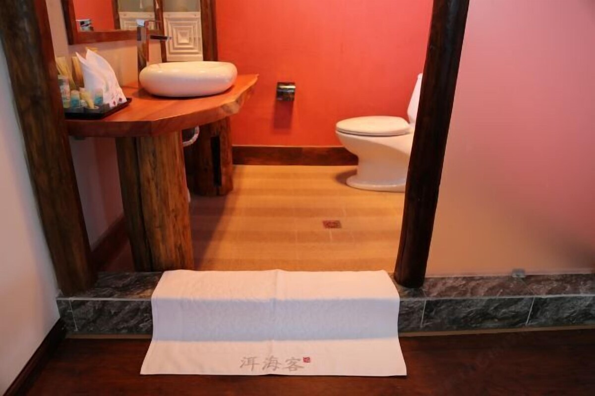 Ein Badezimmer mit einem Holzbadezimmermöbel, einer weißen Toilette und einem Handtuch auf dem Boden.