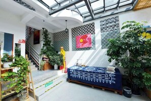 Um quarto com claraboia, escada e sofá azul.