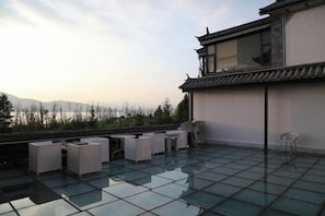 A rooftop terrace with glass flooring, seating arrangements, and a view of distant mountains. - Erhaike Inn (Dali City)
