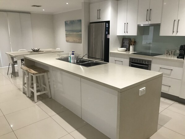 A modern kitchen with a central island, stainless steel appliances, and white cabinetry.