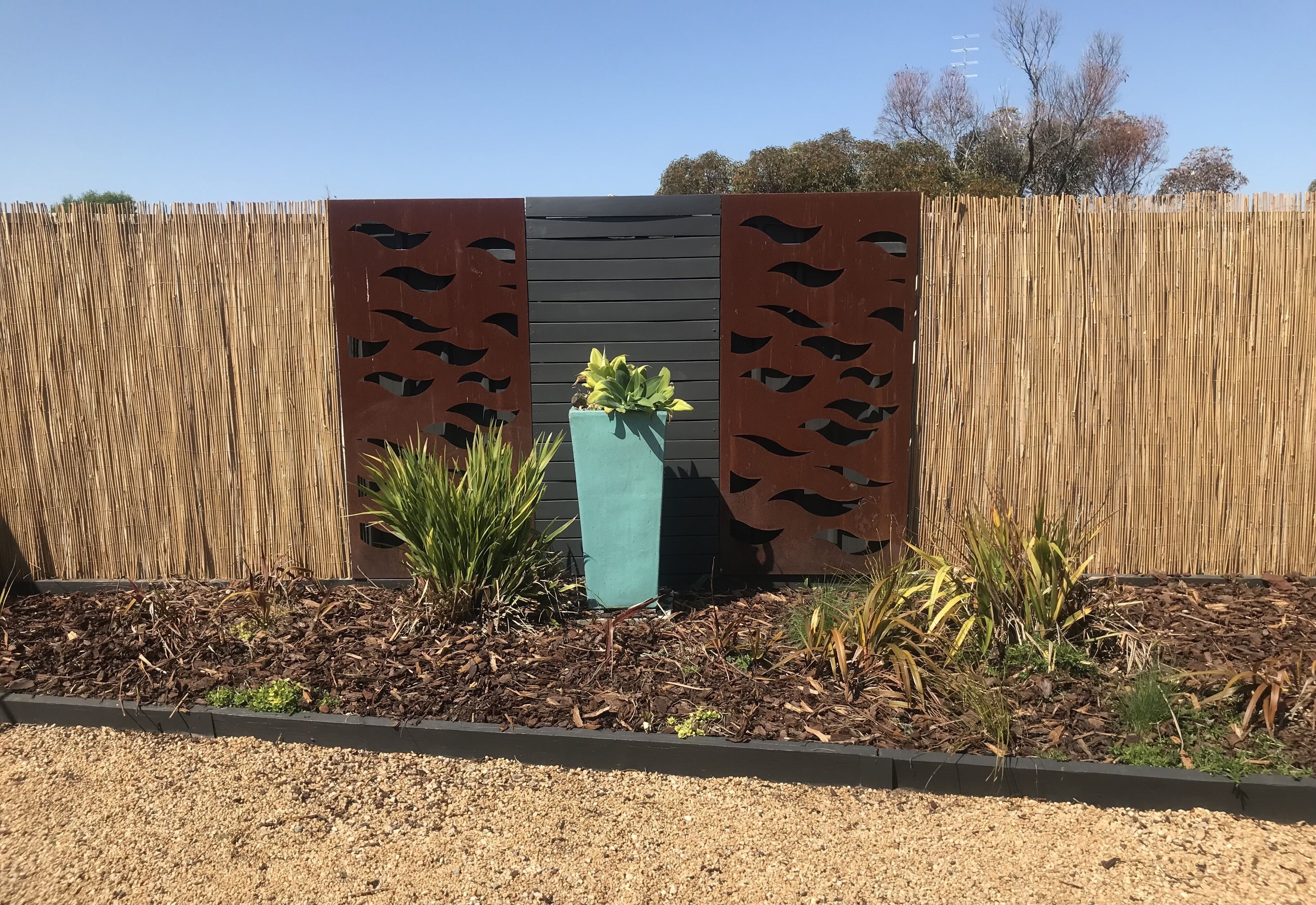 A garden area with a decorative fence, a planter box, and various plants.