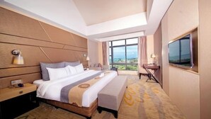 Habitación de hotel con una cama grande, un escritorio, una silla, un televisor y vistas al exterior.