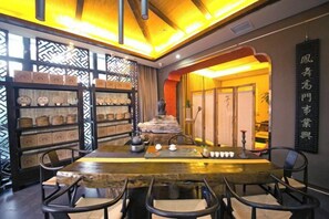 A traditional tea house interior with a long table, chairs, and shelves of tea sets. - Litz Oceanview Hotel (Huandao Road) (Xiamen)