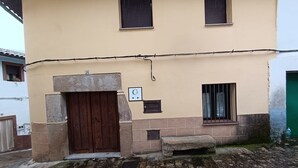 A two-story building with a brown wooden door and windows with bars. - Casa Rural Abuela Maria (Pasarón de la Vera)