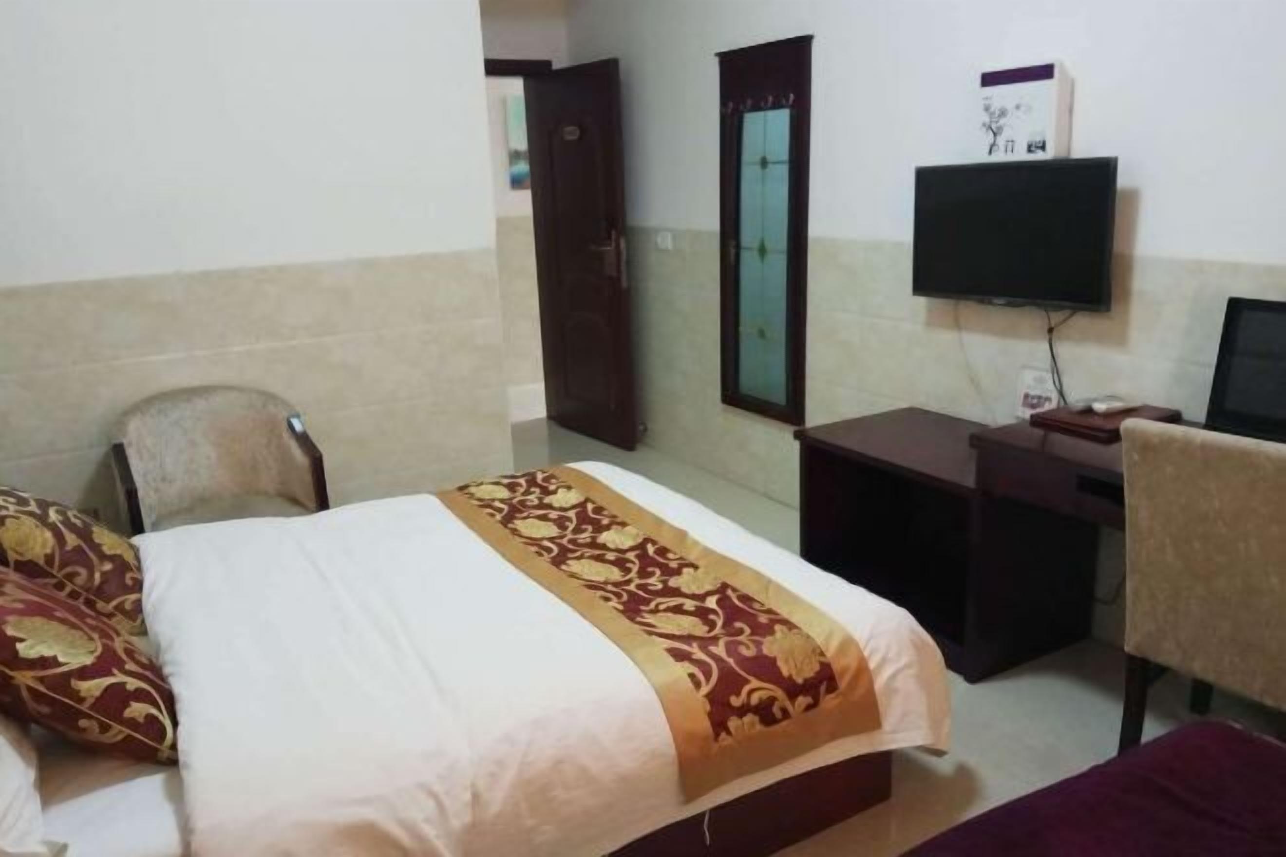 Une chambre d’hôtel équipée d’un lit, d’un bureau, d’une chaise, d’une télévision et d’une armoire.