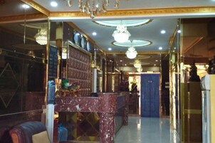 A hotel lobby with a marble reception desk, chandeliers, and a blue wall.