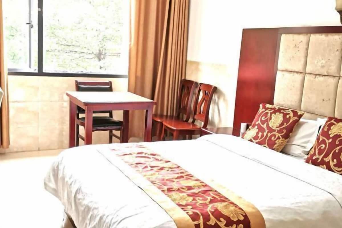 A hotel room with a bed, a table, and two chairs.