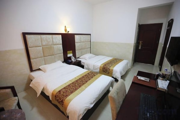 A hotel room with two beds, a desk with a computer, and a door. - XLDSWBG (Xiangxiang)