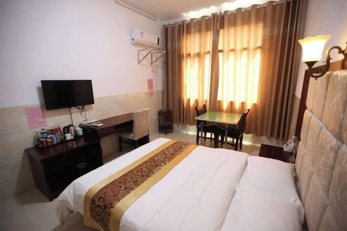A hotel room with a bed, a desk, a television, and a table.