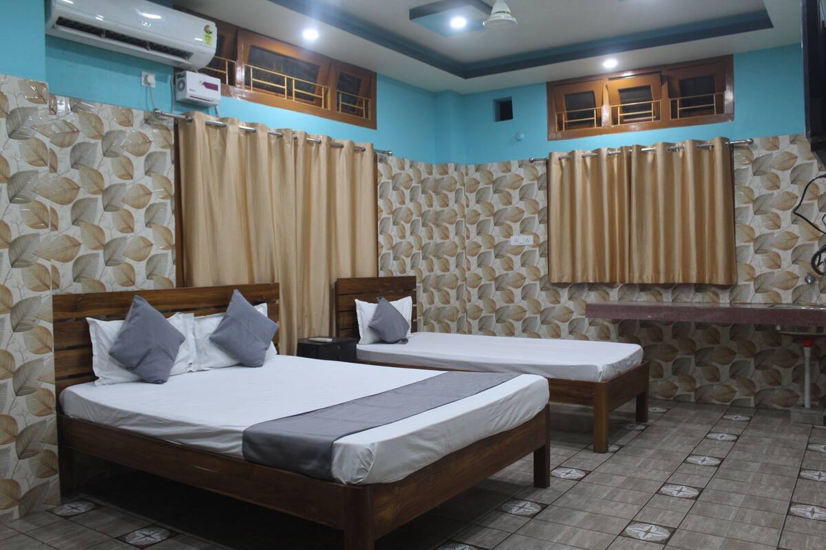 A hotel room with two wooden beds, a small desk, and a bathroom with a shower curtain.